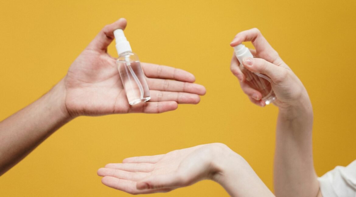 Hands using hand sanitizer against a yellow background, highlighting hygiene.