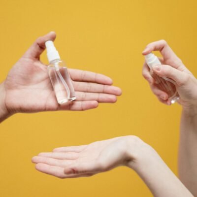 Hands using hand sanitizer against a yellow background, highlighting hygiene.