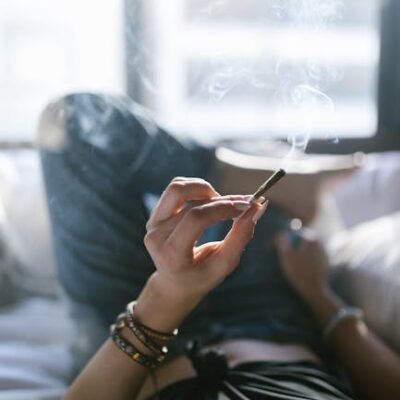 Woman lying on bed smoking a joint, enjoying a peaceful moment.